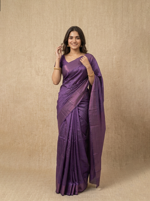 Woman wearing a purple saree against a beige background
