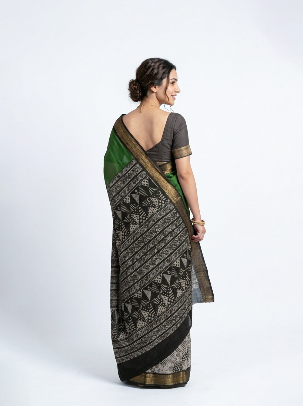Woman in a green saree standing outdoors with trees in the background