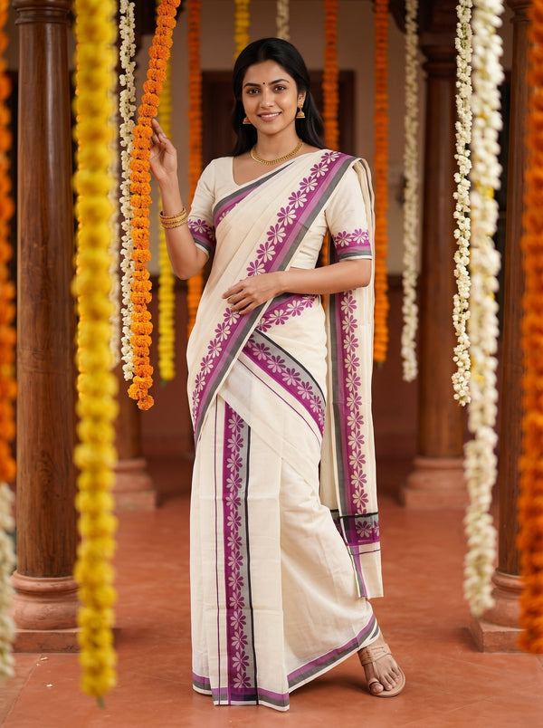 A woman wearing a cream-colored cotton saree with purple and gray border patterns, standing in a corridor decorated with hanging orange and white marigold garlands.