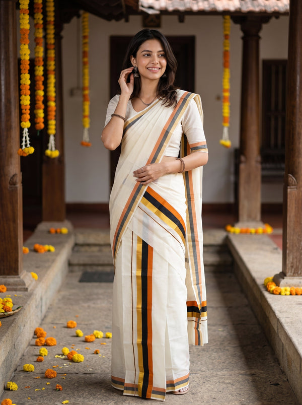 A woman wearing a cream-colored cotton saree with orange, yellow, and black stripes, standing in a traditional courtyard decorated with marigold garlands.