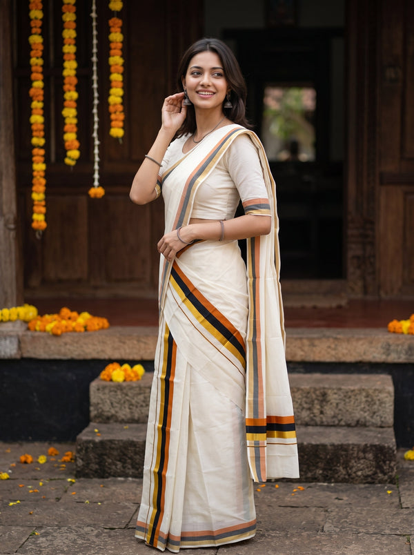 A woman wearing a cream-colored cotton saree with orange, yellow, and black stripes, standing in front of a traditional wooden doorway decorated with marigold garlands.