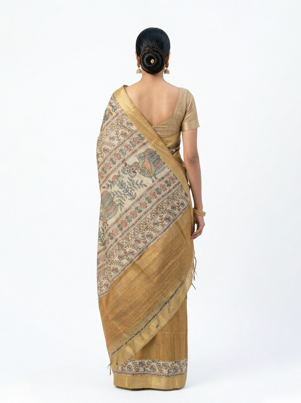 Woman in a traditional mustard yellow saree with a patterned border standing in an elegant hallway.