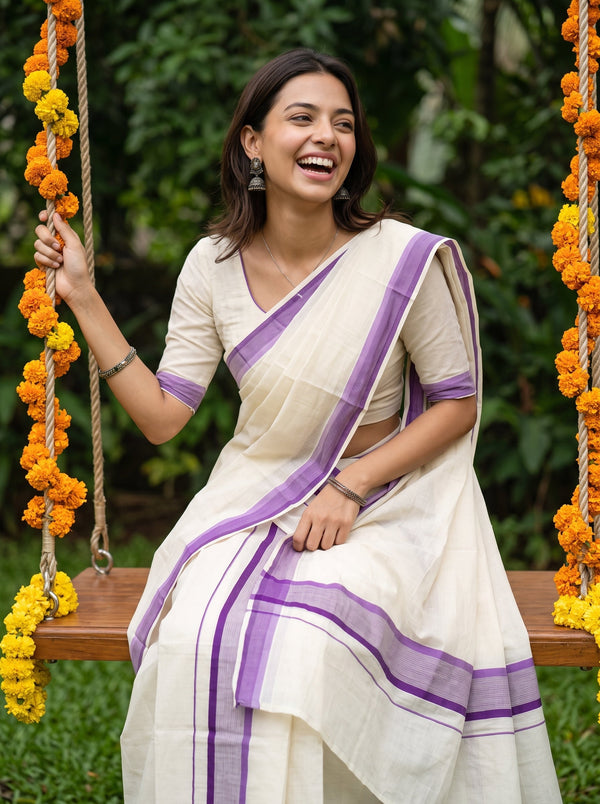 A woman wearing a cream-colored cotton saree with purple borders sits on a wooden swing decorated with orange marigold garlands, set against a lush green garden background.