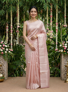 Woman in a pink saree standing in front of floral decorations