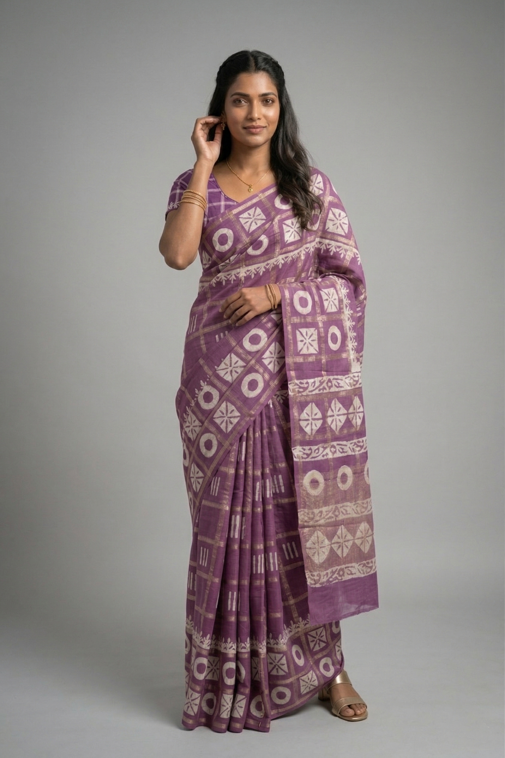 Woman wearing a purple saree with white patterns on a gray background